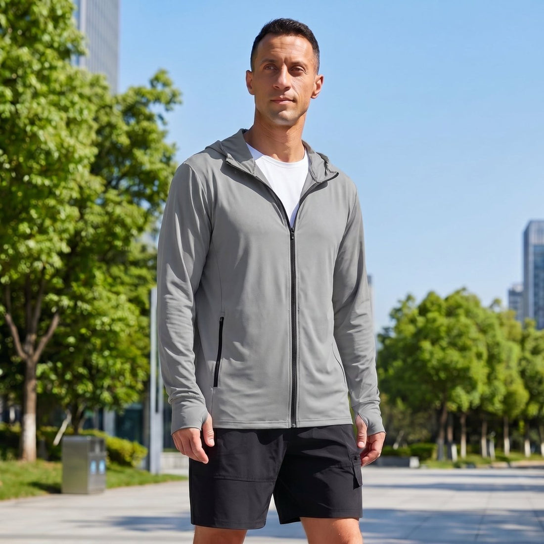 Man wearing a light grey TACVASEN quick-dry hooded jacket outdoors in sunny weather